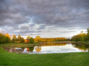 A landscape photographh of purple clouds and a reflecting pond with a red pagoda at kings Park.