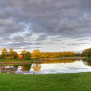A landscape photographh of purple clouds and a reflecting pond with a red pagoda at kings Park.