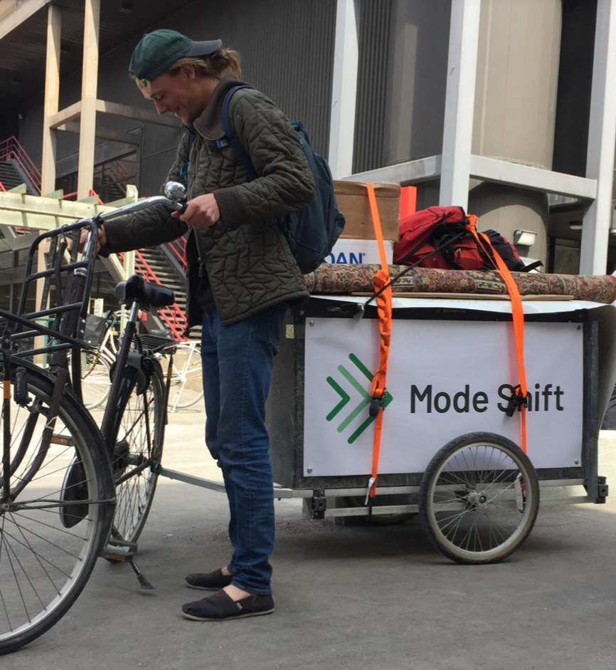 A person getting ready to ride a bike with a Mode Shift trailer on the back.