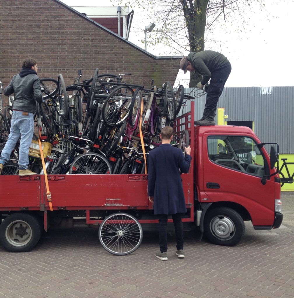 People unloading bicycles from red truck